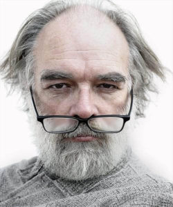 Old man with gray hair and beard wearing reading glasses